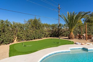 Ein Garten mit Schwimmbad, Kunstrasen und einer Golfplatz-Anlage.