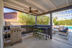 An outdoor patio with a grill, seating, and a view of a swimming pool. - Epic Desert Stay Pool Hot Tub Sports Court (Scottsdale)