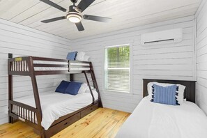 Habitación con literas, ventilador de techo, ventana con persianas y aire acondicionado.