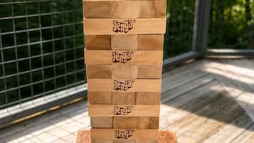 En stabel Jenga-klodser på et træbord med gelænder i baggrunden.