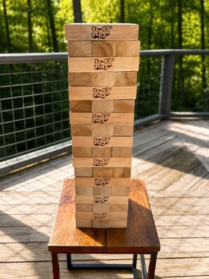 Una pila de bloques de Jenga sobre una mesa de madera con una barandilla de metal al fondo.