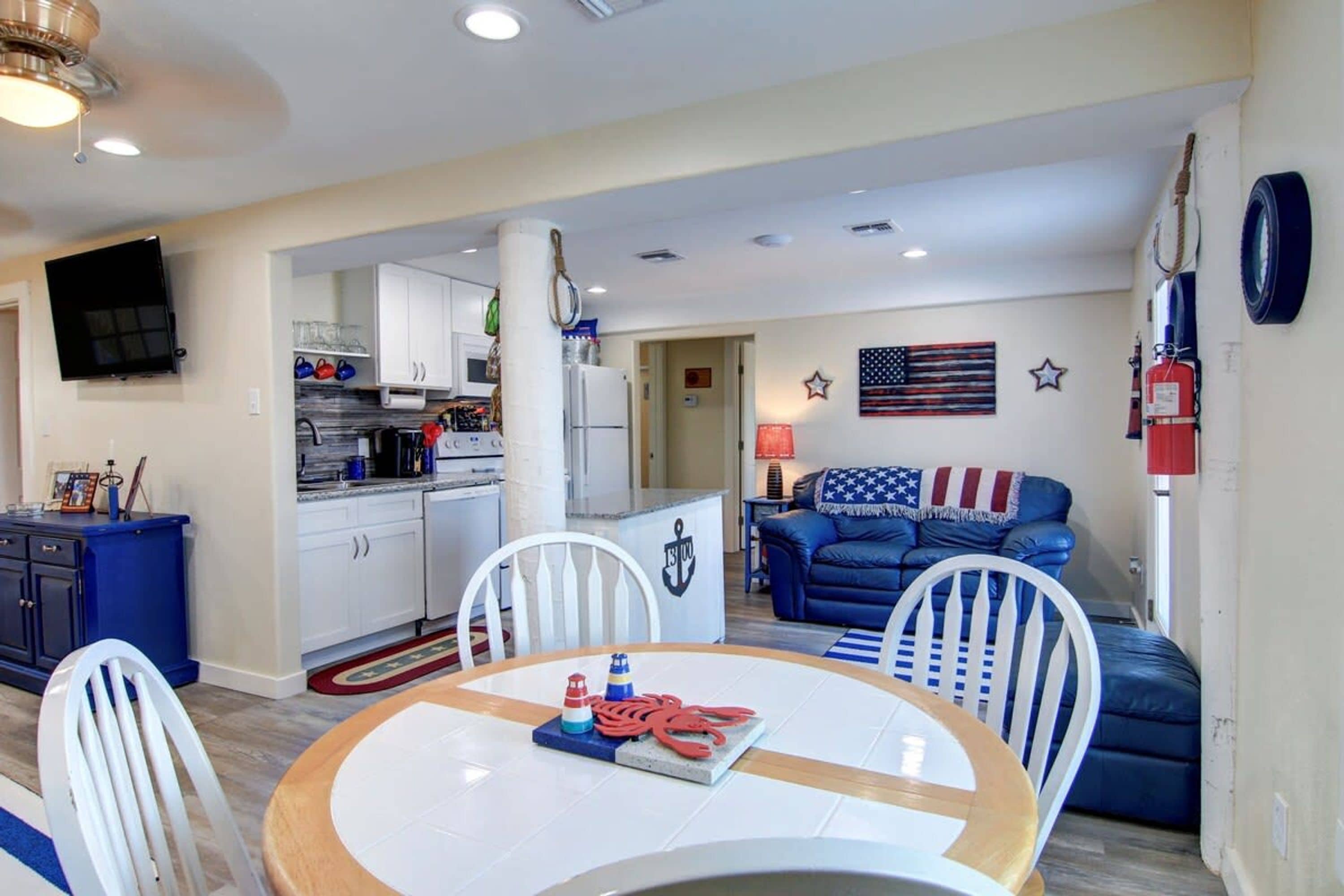 A compact living space with a dining area, kitchen, and a living room with a couch and American flag decoration.