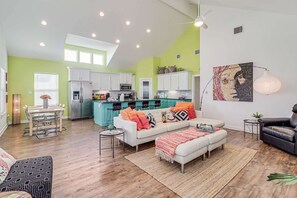 A spacious living area with a dining table, sofa, and a kitchen in the background. - Brito Beach- View of Pond Propane Grill (Port Aransas)