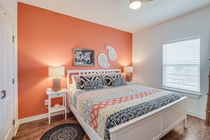 Un dormitorio con cama, dos mesitas de noche, una lámpara de noche, una ventana con persianas y un cuadro en la pared.