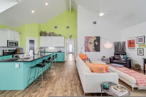 A modern kitchen with a bar area, a dining space with a white sofa, and a living area with a black sofa. - Brito Beach- View of Pond Propane Grill (Port Aransas)