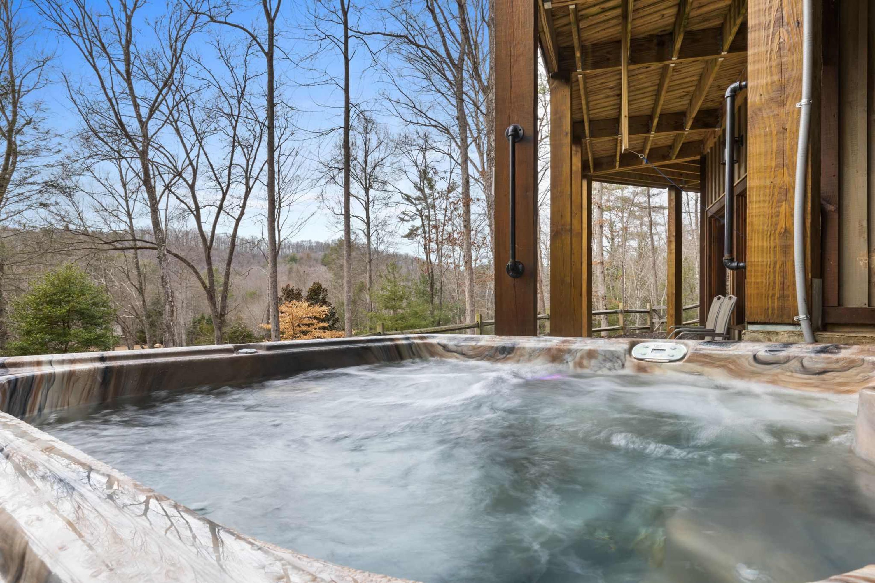 Un bain à remous avec une terrasse en bois et une vue sur les arbres.