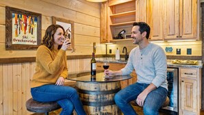 A wooden interior with a round bar table, a wine bottle, and a glass. - Blue Ridge Cabin Stunning Views Hot Tub Game Room (Cherry Log)