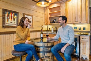 Ein Holzkamin mit einem runden Bartisch, einer Weinflasche und einem Glas.