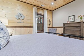 A bedroom with a bed, a chair, a dresser, and a window with curtains. - Blue Ridge Cabin Stunning Views Hot Tub Game Room (Cherry Log)