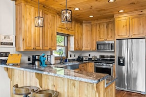 Eine moderne Küche mit Holzschränken, Edelstahlgeräten und einer Arbeitsplatte aus Granit.