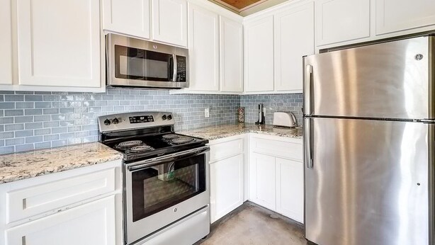 A kitchen with white cabinets, a stainless steel refrigerator, a microwave, and a stove. - Casa Bella- Community Pool View 0 3 mi to Beach (Port Aransas)