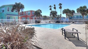 A swimming pool with lounge chairs and a white fence. - Casa Bella- Community Pool View 0 3 mi to Beach (Port Aransas)