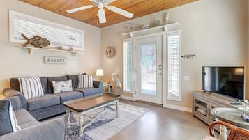 A living room with a ceiling fan, a sofa, a coffee table, and a television.