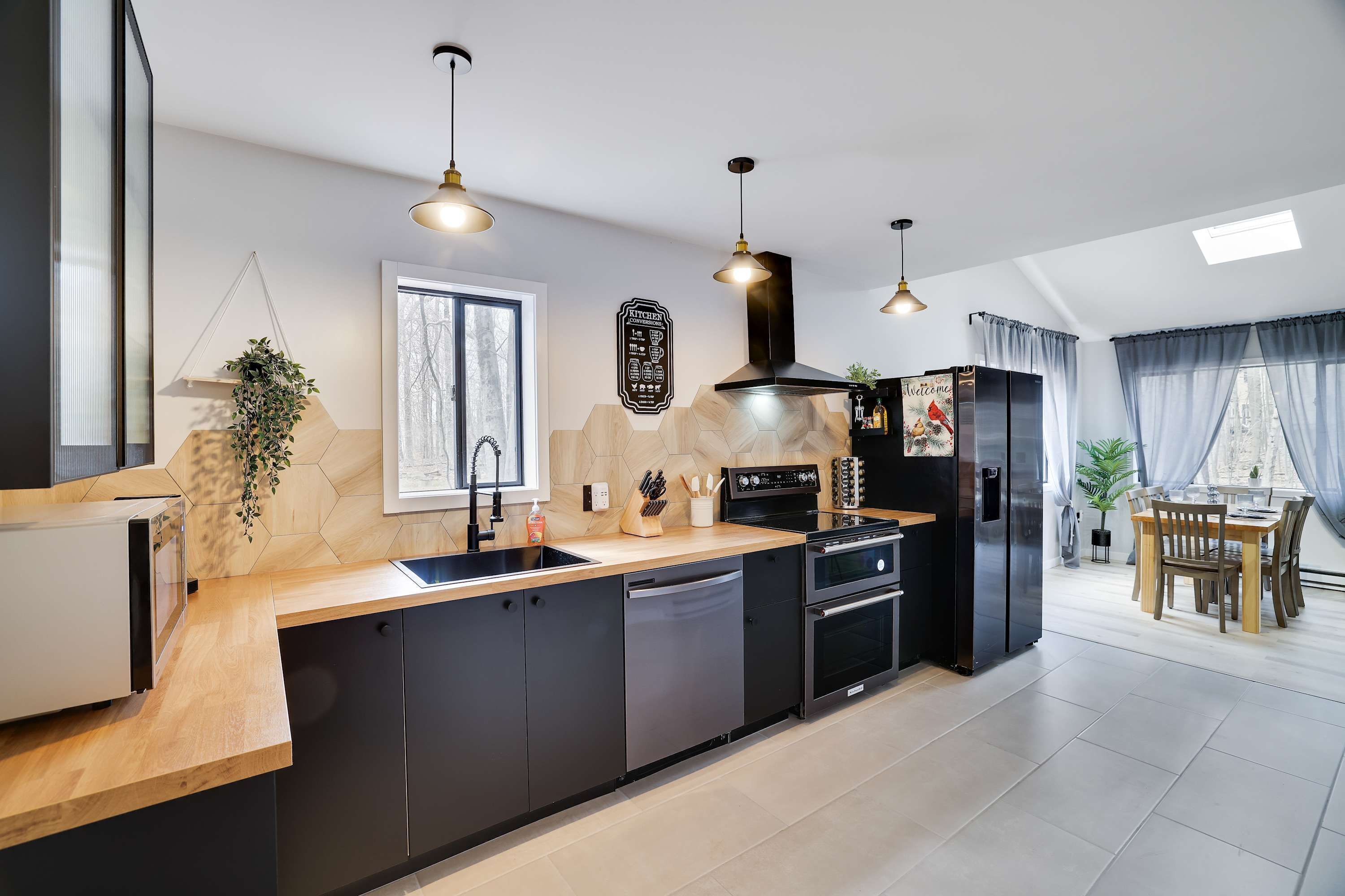 A modern kitchen with a central island, black cabinetry, and pendant lighting.