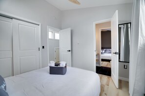 Une chambre à coucher avec un lit, un coffre de rangement, une porte et une vue sur une autre pièce.