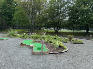 An outdoor area with raised garden beds, a picnic table, and a fenced sports field. - 3BR Home w Outdoor Fun Lake Fire Pit Games Grill (Tobyhanna)