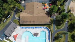 Vista aérea de un edificio con piscina, rodeado de vegetación y un estacionamiento.