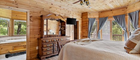 A wooden cabin bedroom with a bed, dresser, and a ceiling fan.