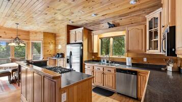 A modern kitchen with wooden cabinetry, stainless steel appliances, and a large island.