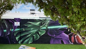 A wall with a large mural, a sign, and a wooden bench on artificial grass. - Casa Citrus 6BR Heated Pool Spa Modern Design (Scottsdale)