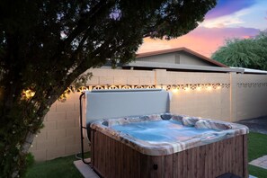 A hot tub in a backyard with a brick wall and string lights. - Casa Citrus 6BR Heated Pool Spa Modern Design (Scottsdale)