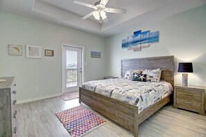 Une chambre à coucher avec un lit, une table de chevet, un ventilateur de plafond et une porte.