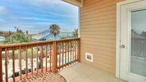 A balcony with a view of a swimming pool and palm trees. - Piggy s Perch- 2 Balconies Direct Pool Access (Port Aransas)