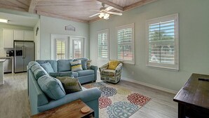 A spacious living room with a sectional sofa, a patterned rug, and a ceiling fan. - Piggy s Perch- 2 Balconies Direct Pool Access (Port Aransas)