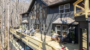 A two-story house with a deck, multiple windows, and outdoor furniture. - 7k sq ft Mountain Estate -the Most Epic Experience (Asheville)