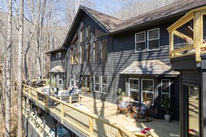 A two-story house with a deck, multiple windows, and outdoor furniture. - 7k sq ft Mountain Estate -the Most Epic Experience (Asheville)