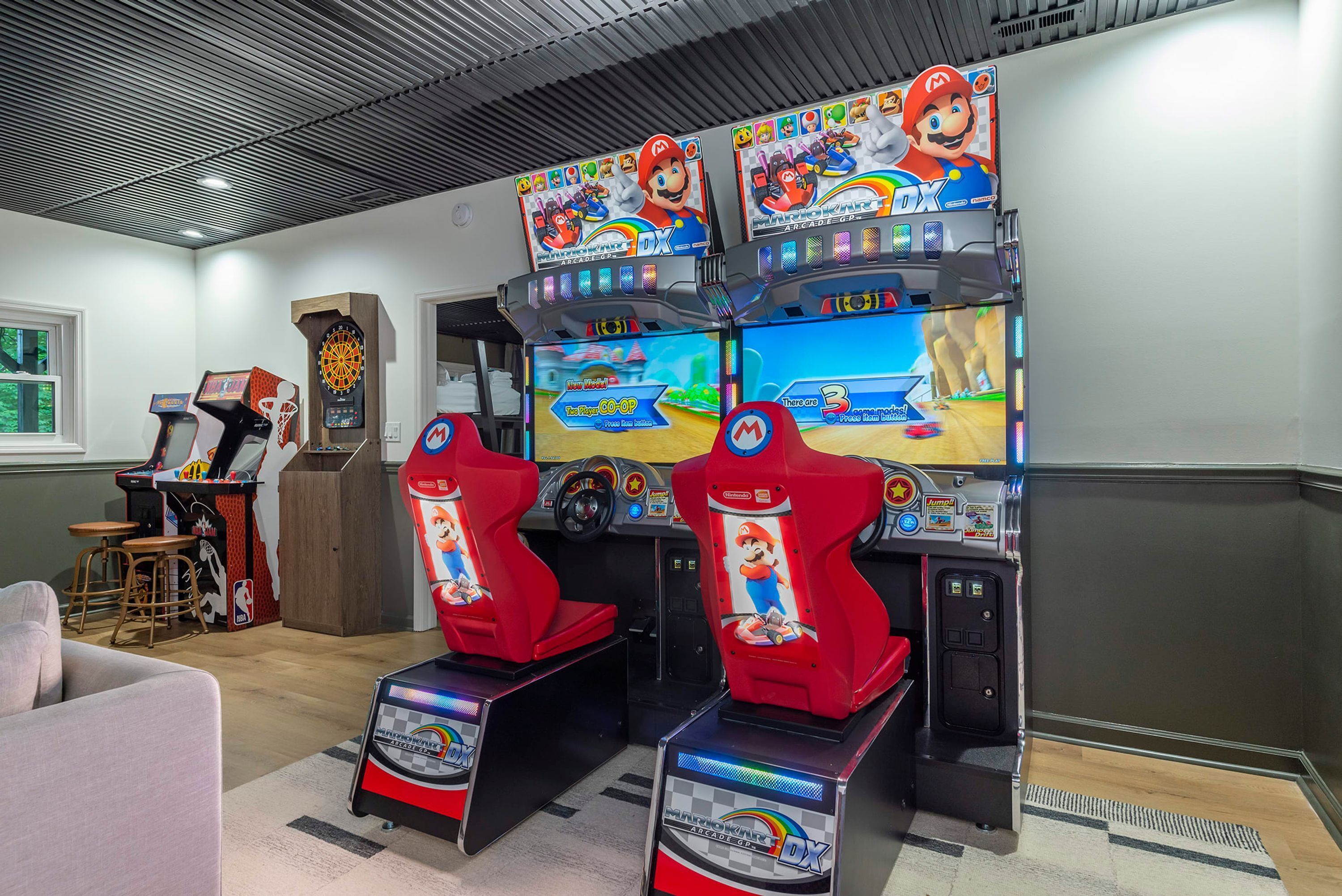 A gaming area with multiple arcade machines, including Mario Kart, and a dartboard.