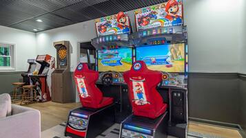 A gaming area with multiple arcade machines, including Mario Kart, and a dartboard.