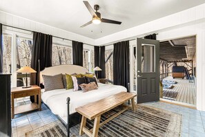 A bedroom with a bed, bedside tables, a bench, a ceiling fan, and a view of a deck with outdoor seating. - 7k sq ft Mountain Estate -the Most Epic Experience (Asheville)