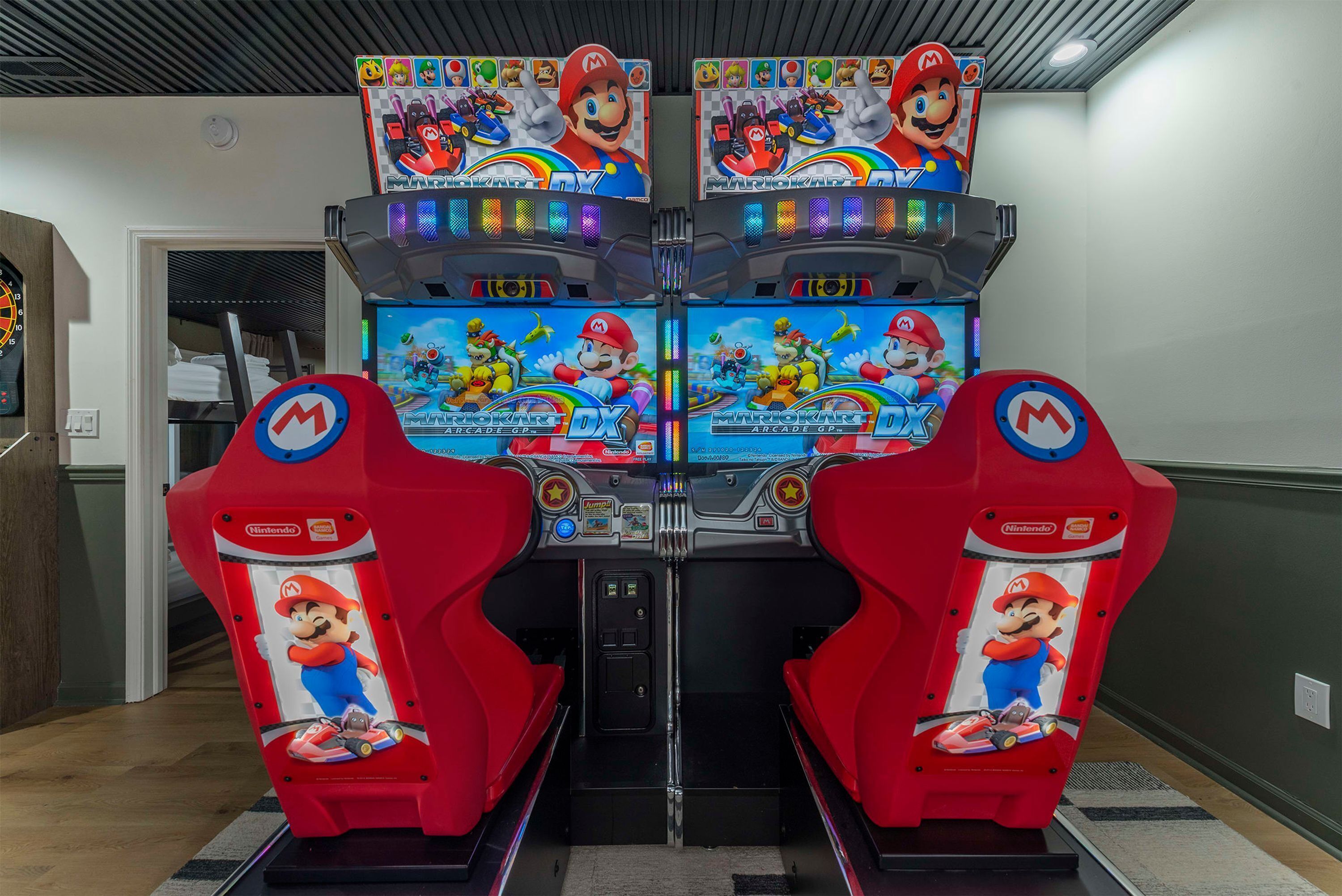 A row of four Mario Kart arcade machines in a hallway.