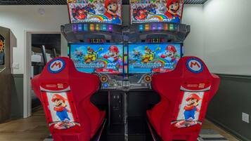 A row of four Mario Kart arcade machines in a hallway.