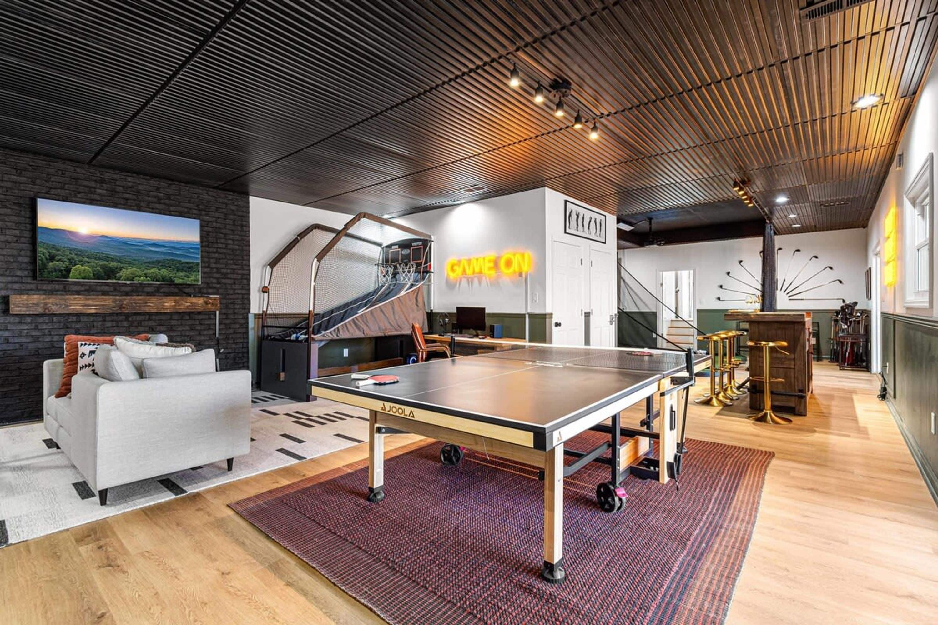 A modern indoor space with a ping pong table, a sofa, and a staircase.