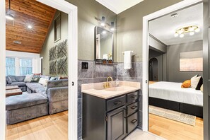 A modern interior with a sofa, a bathroom with a sink, and a bed. - 7k sq ft Mountain Estate -the Most Epic Experience (Asheville)