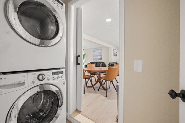 Un cuarto de lavandería con lavadoras apiladas y un comedor con mesa y sillas.