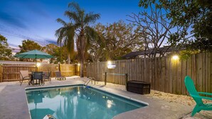 Um quintal com piscina, cerca de madeira e móveis de exterior.