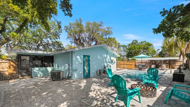 Um quintal com piscina, móveis de jardim e uma pequena construção.