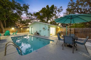 A backyard with a swimming pool, patio furniture, and a covered outdoor area. - 3 Miles to Honeymoon Island Firepit Pool (Palm Harbor)