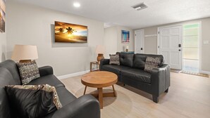 Uma sala de estar com um sofá, uma mesa de centro e um quadro na parede.