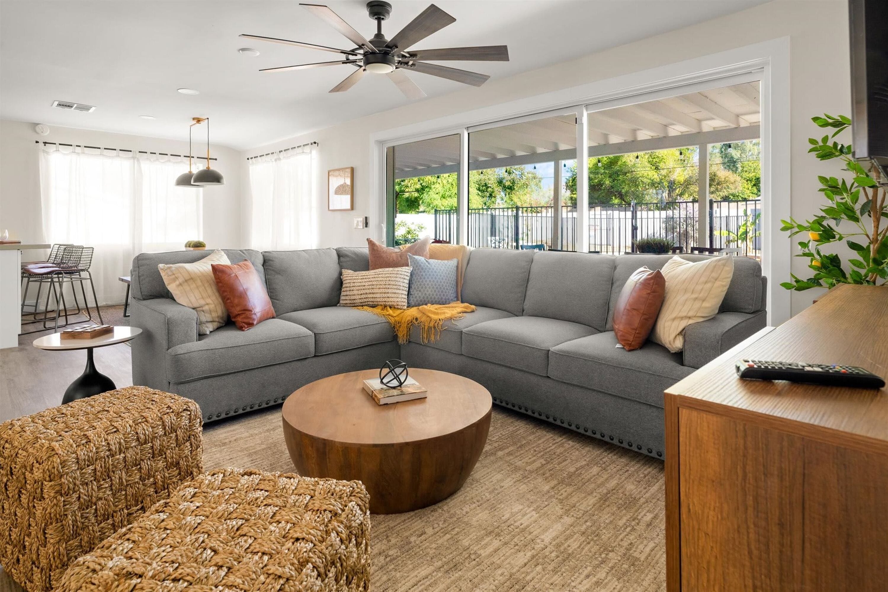 A modern living room with a sectional sofa, a round coffee table, and a ceiling fan.
