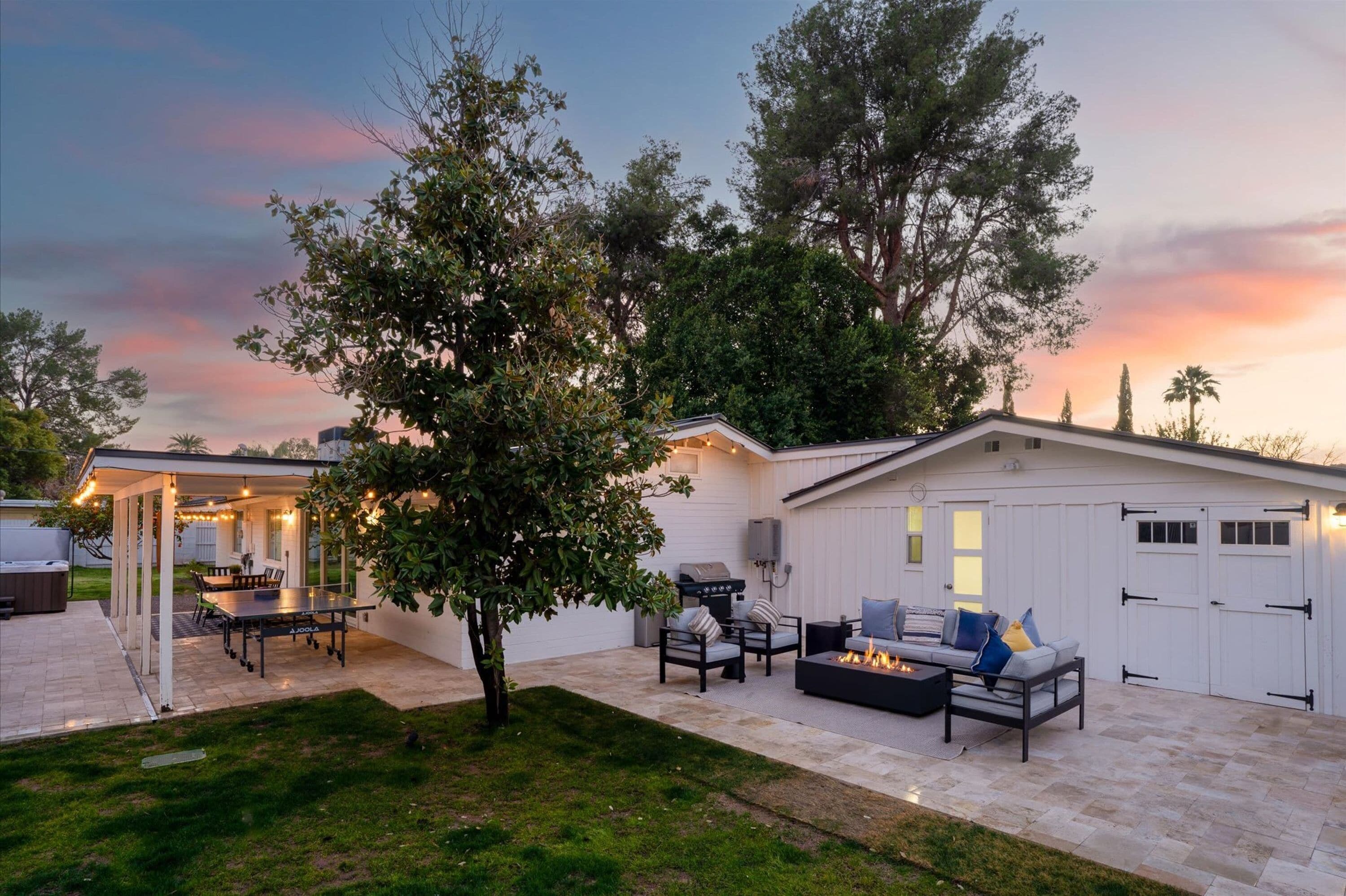 A covered outdoor patio with a ping pong table, seating area, and a barbecue grill.