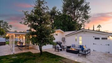 A covered outdoor patio with a ping pong table, seating area, and a barbecue grill.