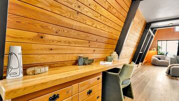 A modern interior with a wooden wall panel, a wooden counter, a chair, and a sofa.