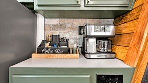 Cozinha com bancada de café, cafeteira Farberware e painel de pedra atrás do fogão.