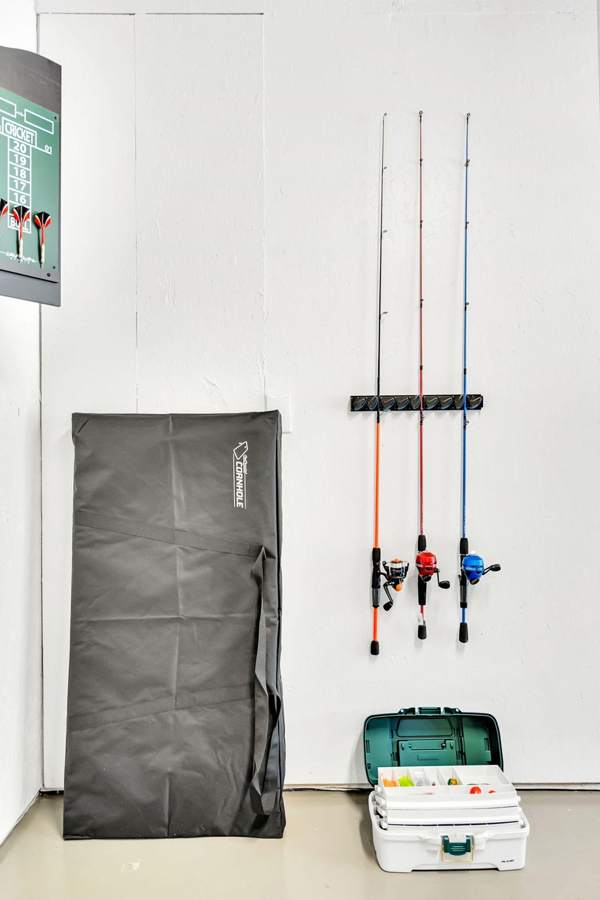 Een kamer met een witte muur, een zwarte tas en hengels.