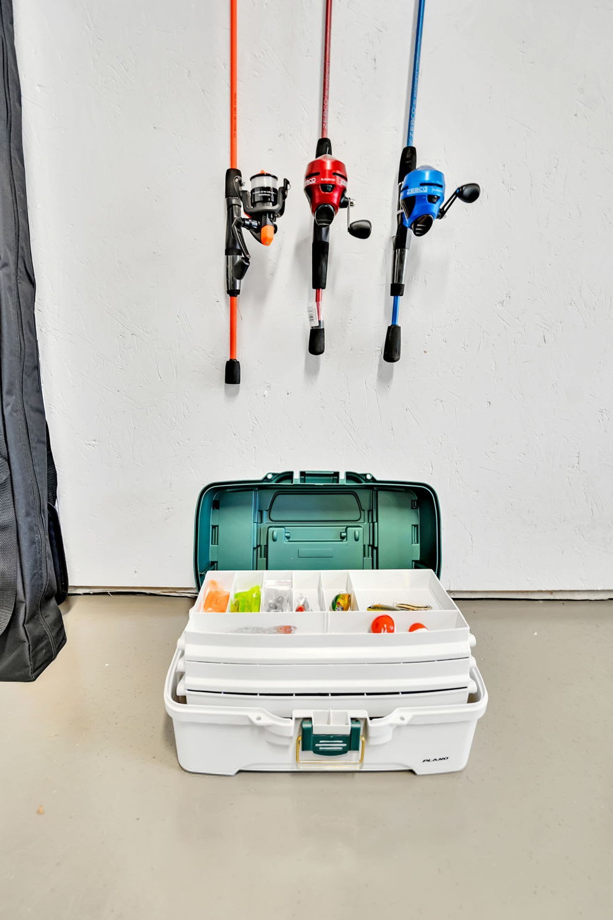 A white fishing rod case with compartments containing fishing gear and a fishing rod.