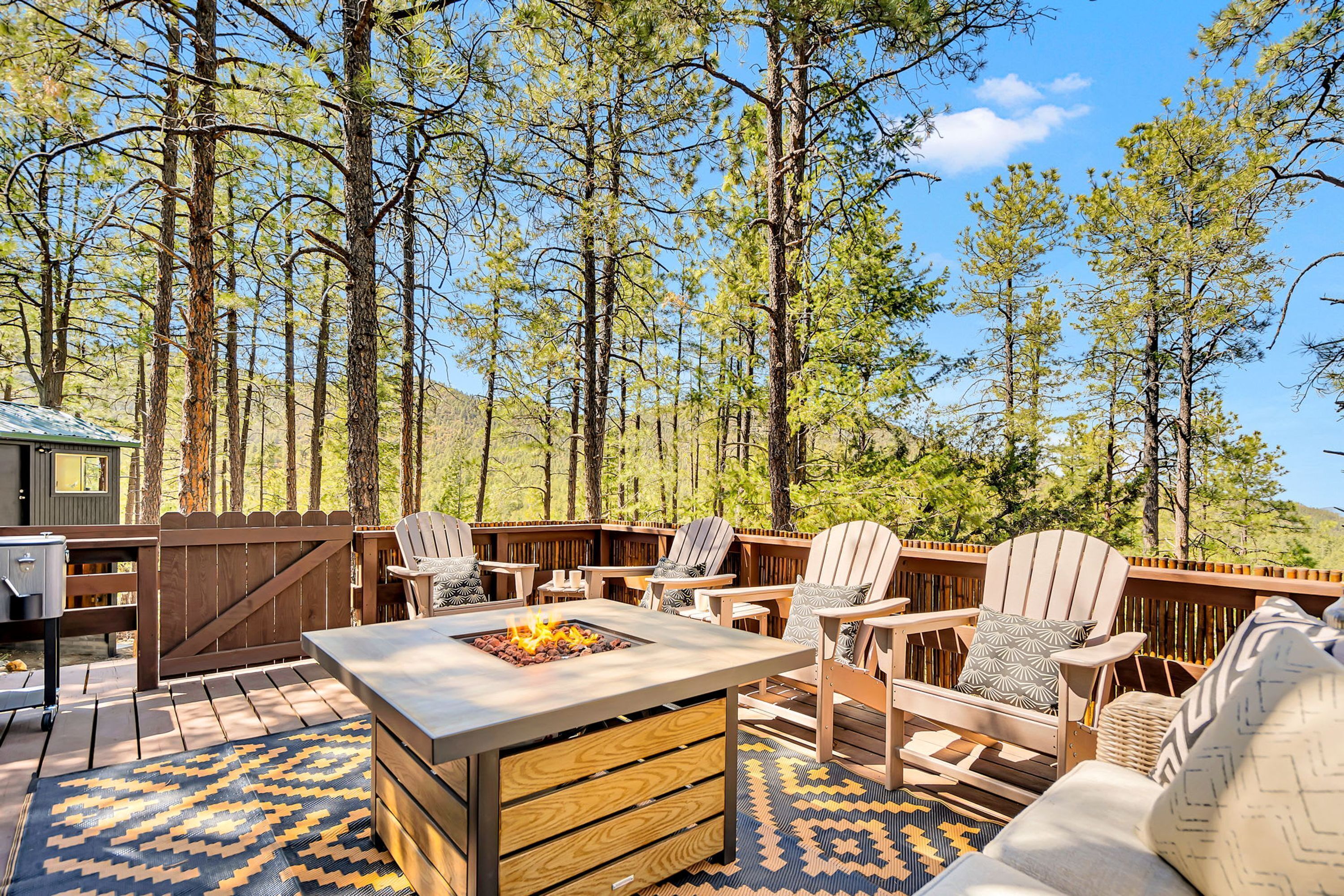 An outdoor seating area with Adirondack chairs, a fire pit, and a wooden deck.